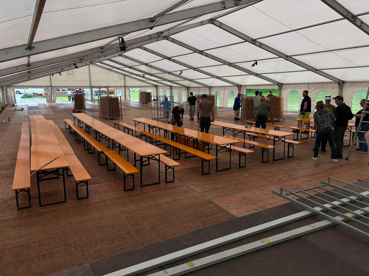Tische und Bänke in einem Festzelt.